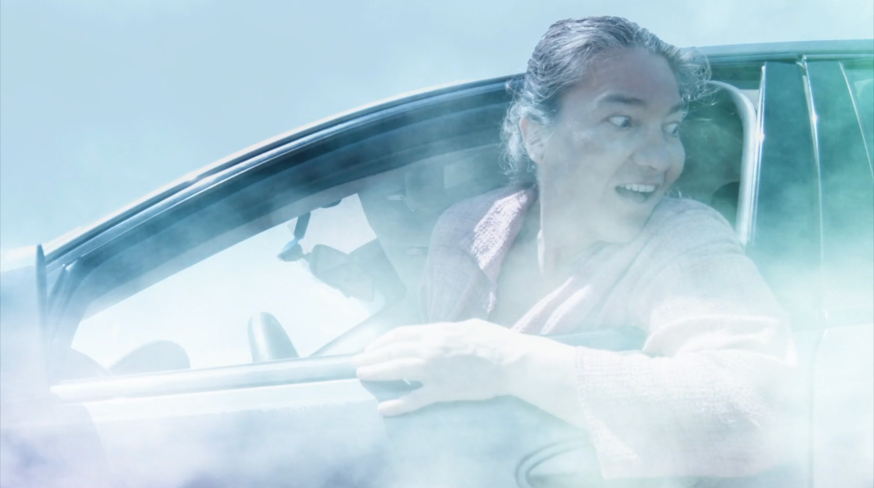 Screenshot from The Last Bark, medium closeup of Zuzana looking back from the car flying in the clouds